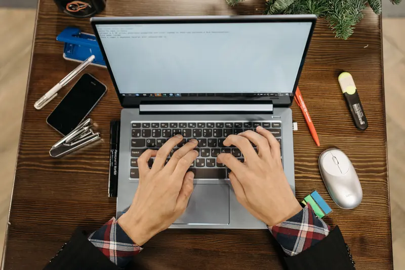 Hands typing on a laptop at a desk.