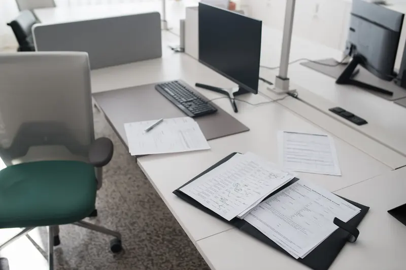 An open document binder and loose papers beside a keyboard on an office desk.