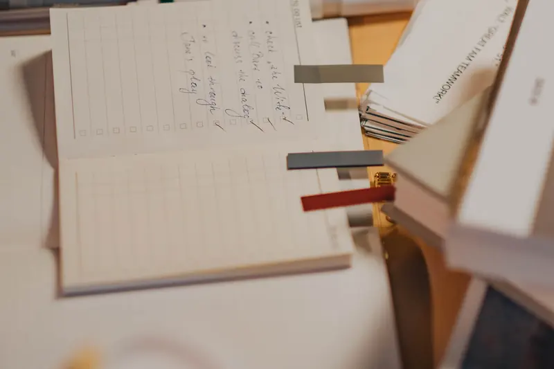 An open notebook with handwritten notes and coloured page tabs on a desk.