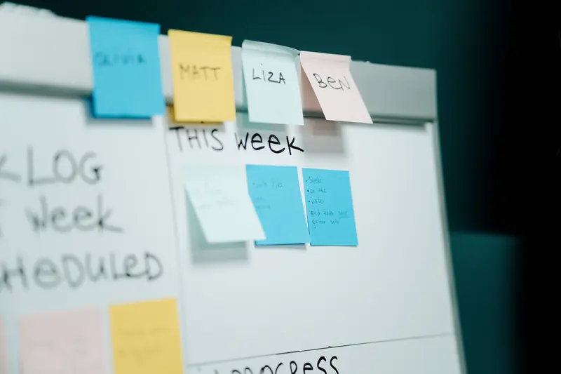 Coloured sticky notes arranged on a whiteboard with a weekly work queue.